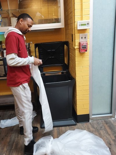 a man smiling while he replaces the trash bag in a trash can