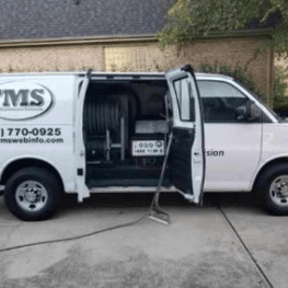 TMS service van parked in driveway with doors open showing property maintenance equipment.